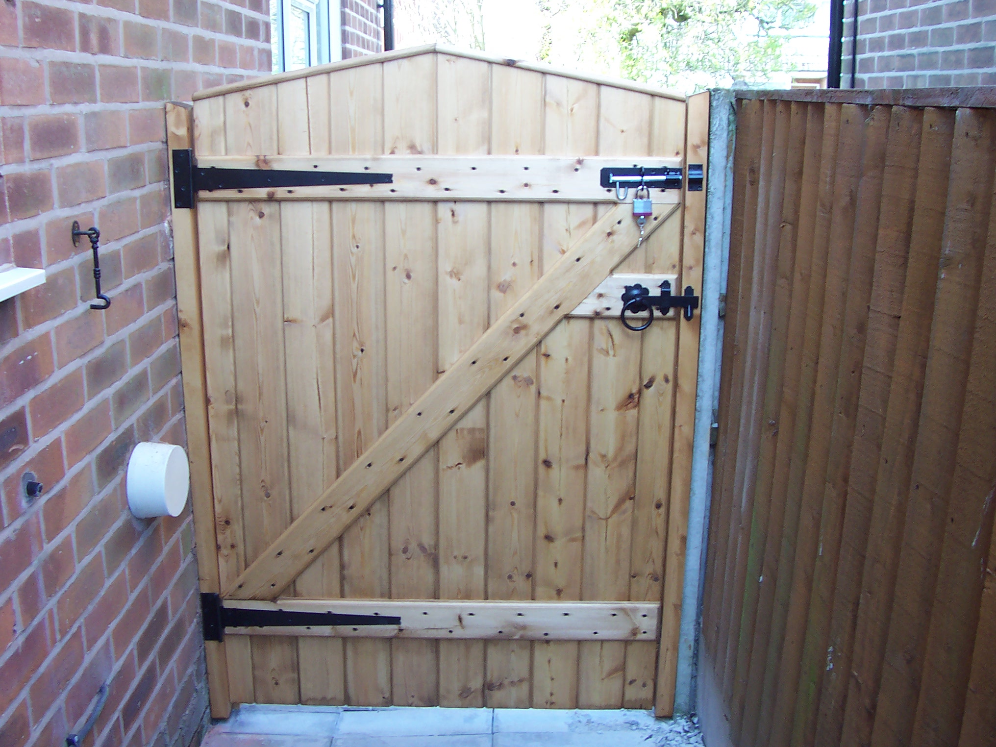 back of a wooden gate with black hinges and padlock