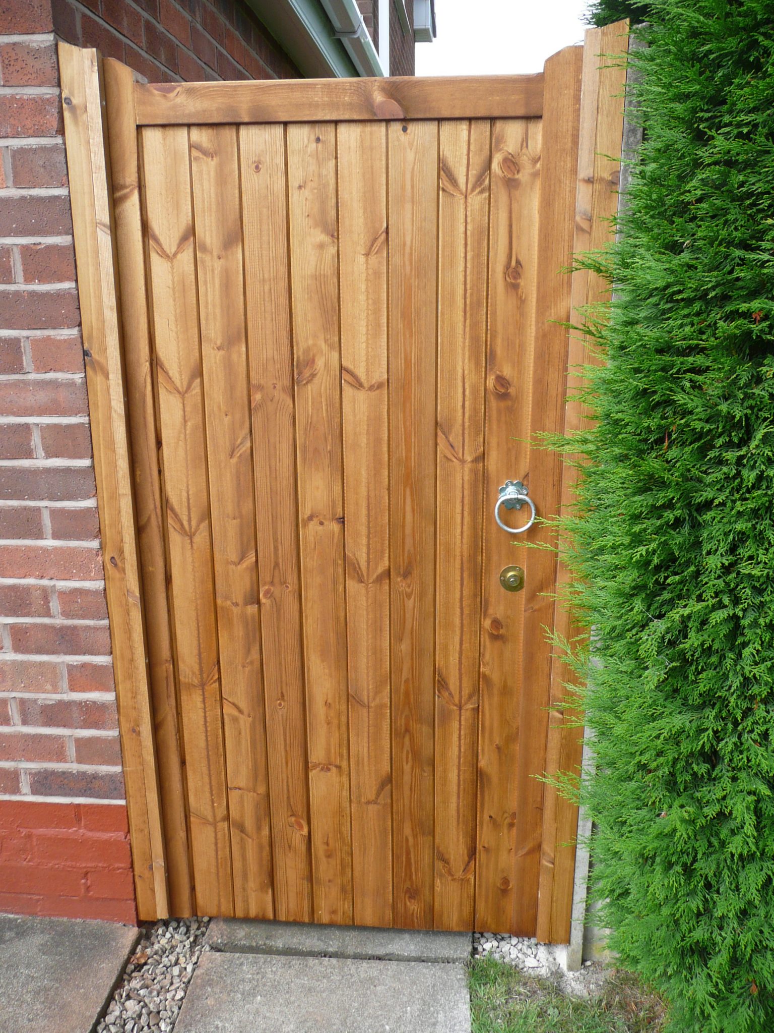 wooden gate next to a large green bush